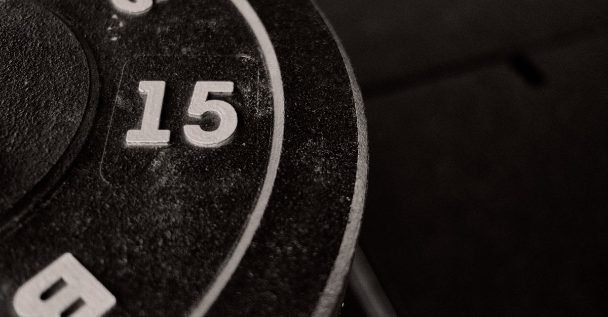 Detailed close-up of a 15-pound weight plate in a gym setting, perfect for workout enthusiasts.
